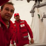 Rotkreuz-Techniker bei der Installation der Hygieneeinheit im Behandlungszelt
